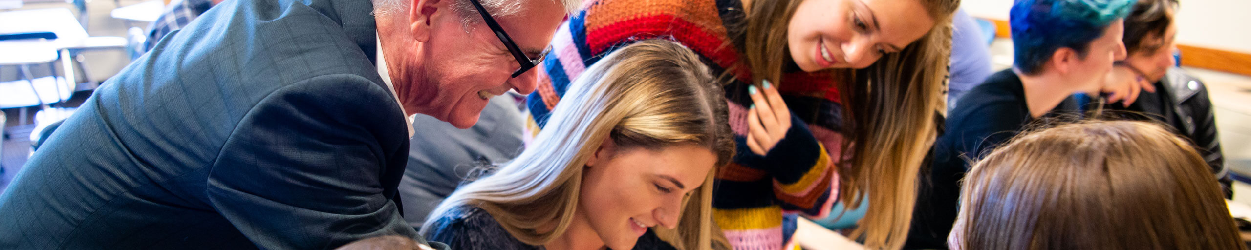 A professor helps a group of students on their assignment.